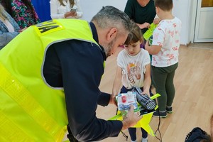 Na zdjęciu widzimy policjanta przekazującego odblaski uczestnikom quizu