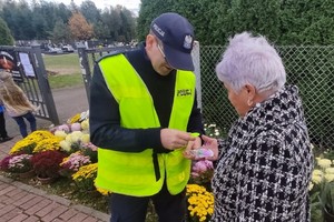 Na zdjęciu widzimy policjanta jak daje seniorce odblask