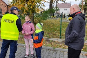 Na zdjęciu widzimy policjanta jak daje dzieciom odblaski