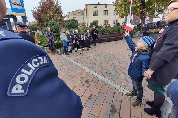 Na zdjęciu widzimy napis Policja oraz dziecko machające flagą Polski