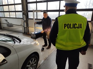 Na zdjęciu widzimy Policjanta w czasie ogólnopolskiej akcji &quot;Twoje światła nasze bezpieczeństwo&quot; na stacji diagnostycznej w czasie sprawdzania oświetlenia w pojeździe