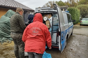 Na zdjęciu widzimy jak pracownicy przystani pomagają rozpakować załadowany darami radiowóz policji