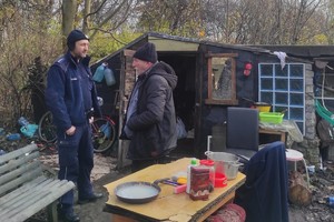 Na zdjęciu widzimy policjanta rozmawiającego z osobą bezdomną