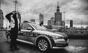 Na zdjęciu widzimy policjanta stojącego przy radiowozie oddającego cześć poległym policjantom