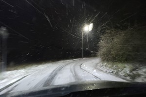 Na zdjęciu widzimy zaśnieżoną drogę w nocy