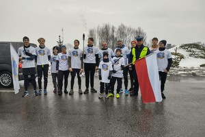 Na zdjęciu widzimy policjanta oraz osoby uczestniczące w biegu