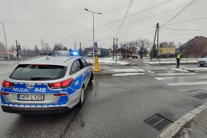 Na zdjęciu widzimy policjanta zamykającego ruch, osoby uczestniczące w biegu oraz radiowóz