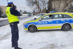 Na zdjęciu widzimy policjanta oraz radiowóz oznakowany