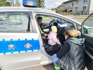 Na zdjęciu widzimy policjanta oraz dziecko siedzące w radiowozie