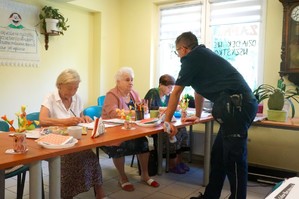 Na zdjęciu widzimy policjanta rozmawiającego z seniorami