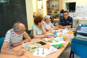 Na zdjęciu widzimy policjanta rozmawiającego z seniorami