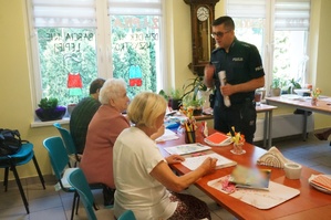 Na zdjęciu widzimy policjanta rozmawiającego z seniorami