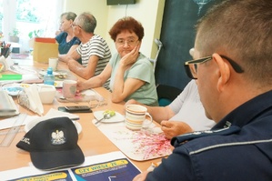 Na zdjęciu widzimy policjanta rozmawiającego z seniorami