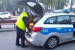 Na zdjęciu widzimy policjanta oraz radiowóz