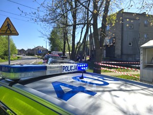Na zdjęciu widzimy policjanta oraz wóz straży pożarnej oraz miejsce wybuchu butli z gazem