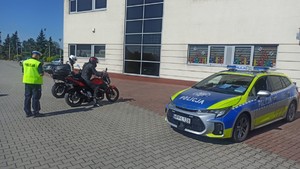 Na zdjęciu widzimy policjanta, radiowóz oraz motocyklistów w czasie kontroli