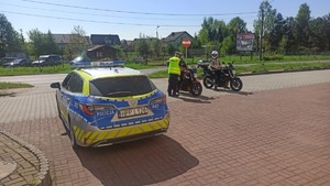 Na zdjęciu widzimy policjanta, radiowóz oraz motocyklistów w czasie kontroli