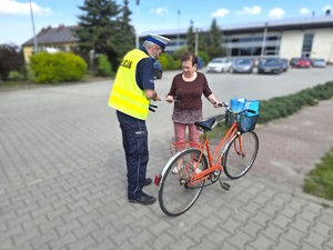 Na zdjęciu widzimy policjanta dającego element odblaskowy pieszym