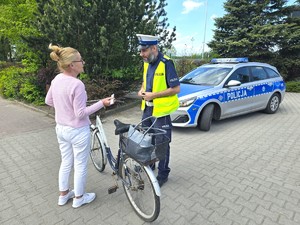 Na zdjęciu widzimy policjanta dającego element odblaskowy pieszym