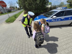Na zdjęciu widzimy policjanta dającego element odblaskowy pieszym