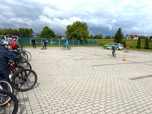 Na zdjęciu widzimy policjanta oraz uczniów zdających egzamin na kartę rowerową