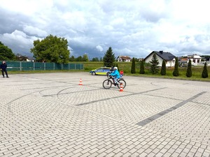 Na zdjęciu widzimy policjanta oraz uczniów zdających egzamin na kartę rowerową