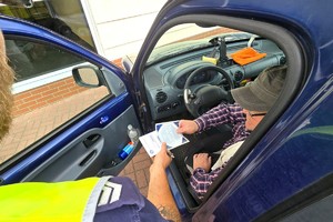 Na zdjęciu widzimy policjanta oraz kierującego z ulotkami oraz naklejką Mistrzu Zwolnij