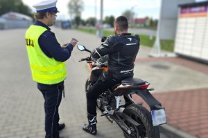 Na zdjęciu widzimy policjanta w czasie kontroli kierującego jednośladem