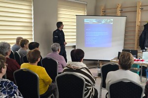 Na zdjęciu widzimy policjanta oraz seniorów w czasie debaty