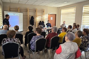 Na zdjęciu widzimy policjanta oraz seniorów w czasie debaty