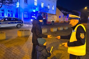 Na zdjęciu widzimy policjanta rozdającego odblaski