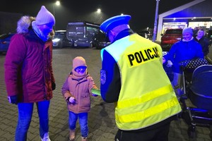 Na zdjęciu widzimy policjanta rozdającego odblaski