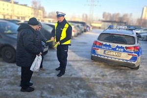 Na zdjęciu widzimy policjanta wręczającego odblaski seniorom