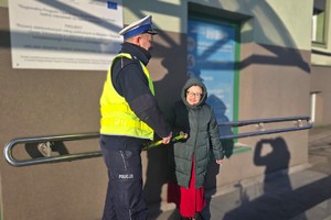 Na zdjęciu widzimy policjanta wręczającego odblaski seniorom