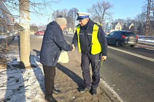 Na zdjęciu widzimy policjanta wręczającego odblaski seniorom