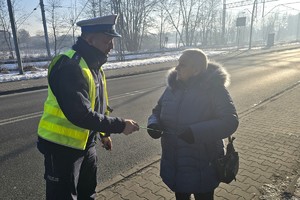 Na zdjęciu widzimy policjanta wręczającego odblaski seniorom