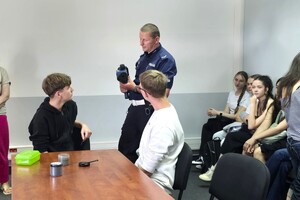 Na zdjęcu widzimy policjanta oraz uczniów w czasie prelekcji przeprowadzonej na terenie bieruńskiej komendy