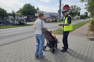 Na zdjęciu widzimy policjanta dającego odblask pieszym