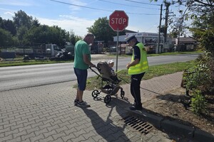 Na zdjęciu widzimy policjanta dającego odblask pieszym