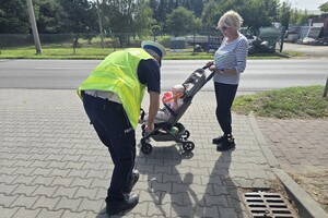 Na zdjęciu widzimy policjanta dającego odblask pieszym