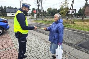 Na zdjęciu widzimy policjanta rozdającego odblaski