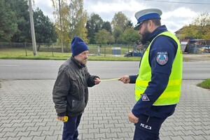 Na zdjęciu widzimy policjanta rozdającego odblaski